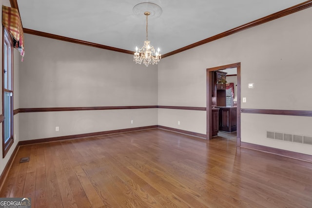 empty room with visible vents, crown molding, baseboards, an inviting chandelier, and hardwood / wood-style flooring