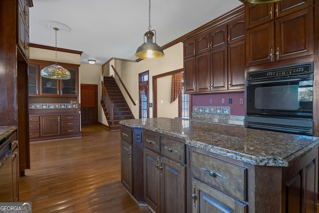 kitchen with glass insert cabinets, decorative light fixtures, wood finished floors, and a center island