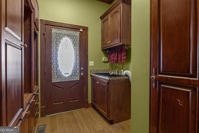 laundry area featuring light wood finished floors, visible vents, and a sink