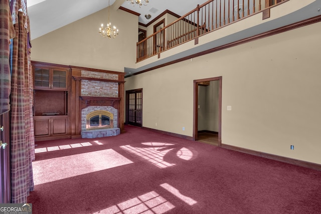 unfurnished living room with baseboards, a chandelier, carpet floors, a stone fireplace, and a high ceiling