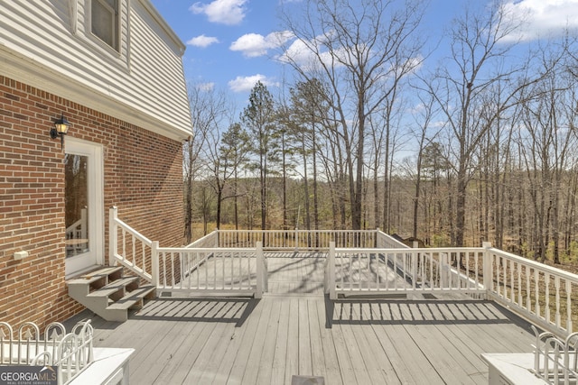 wooden deck featuring entry steps and a forest view