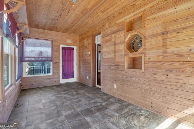 unfurnished room featuring wood ceiling and wood walls