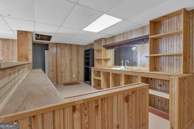 bar with wood walls, a paneled ceiling, and a sink