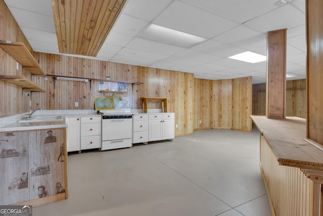 kitchen with a sink, open shelves, finished concrete floors, wooden walls, and stove