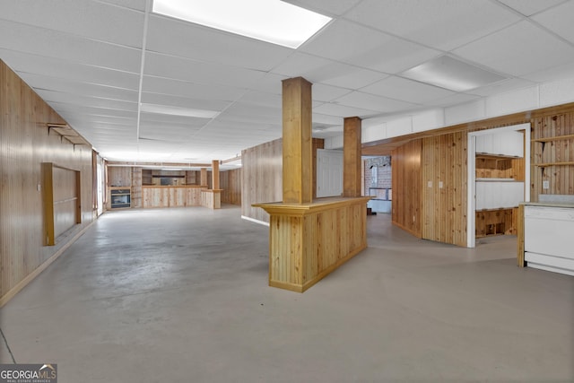 finished basement featuring wooden walls and a drop ceiling