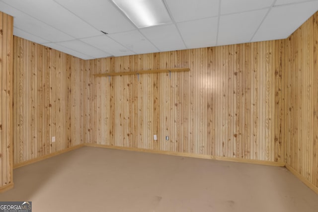 empty room with wooden walls and a paneled ceiling