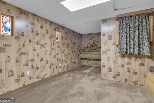 basement with wallpapered walls, carpet flooring, and a paneled ceiling