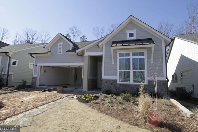 view of front of home with central AC unit, metal roof, a garage, stone siding, and a standing seam roof