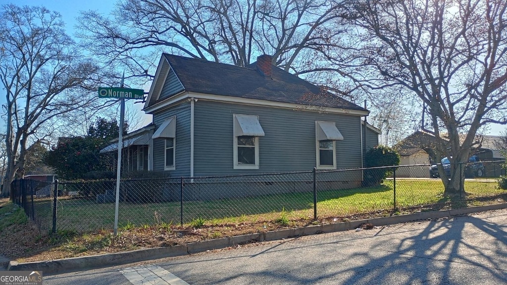 view of home's exterior featuring a lawn, a fenced front yard, and a chimney