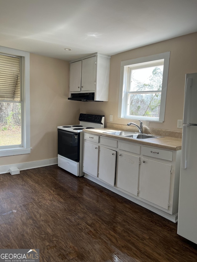 kitchen featuring dark wood-type flooring, light countertops, freestanding refrigerator, electric stove, and a sink