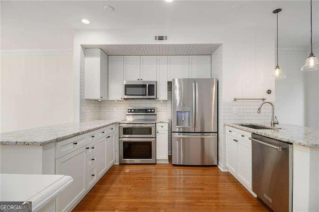 kitchen featuring visible vents, appliances with stainless steel finishes, a peninsula, and a sink