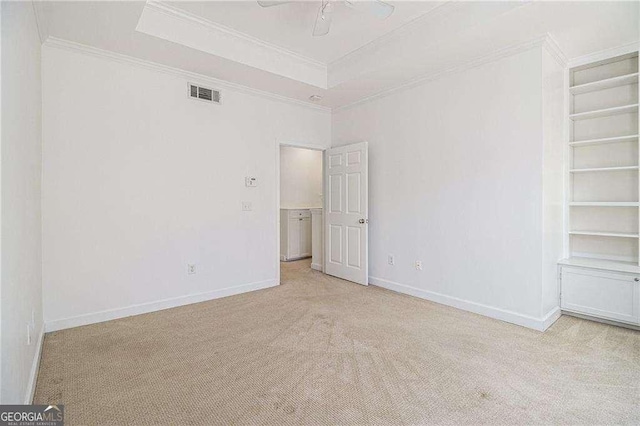 interior space with visible vents, crown molding, a raised ceiling, and baseboards