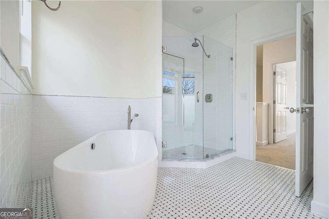 bathroom with tile patterned floors, a wainscoted wall, a stall shower, tile walls, and a freestanding bath