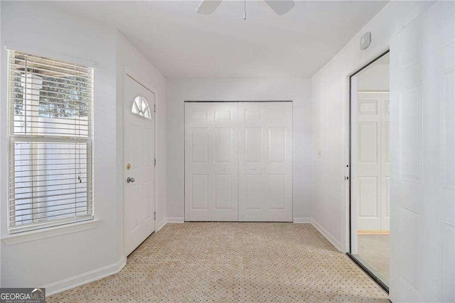 foyer entrance featuring baseboards and a ceiling fan