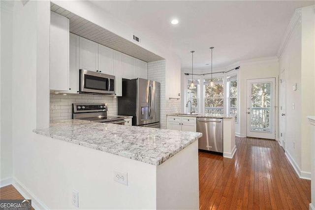 kitchen featuring stainless steel appliances, tasteful backsplash, dark wood-type flooring, and a peninsula