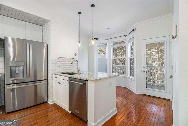 kitchen featuring dark wood finished floors, a sink, stainless steel appliances, white cabinetry, and crown molding