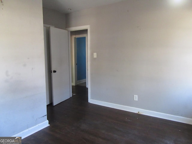 spare room featuring baseboards and wood finished floors