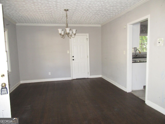 spare room featuring an inviting chandelier, baseboards, dark wood-type flooring, and ornamental molding