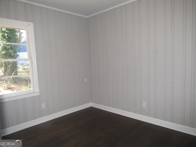 unfurnished room featuring dark wood finished floors, crown molding, and baseboards