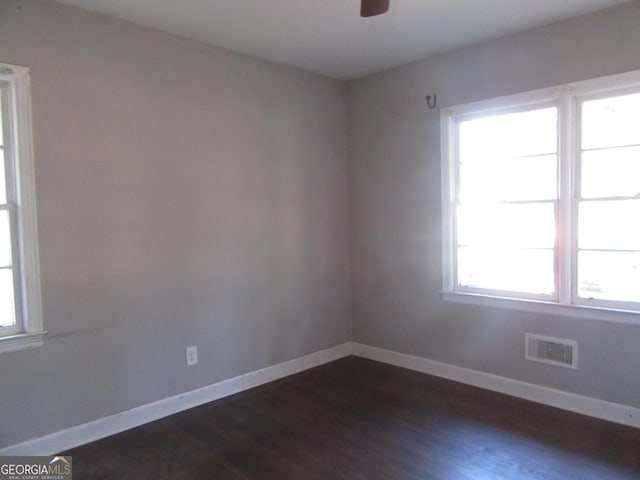 unfurnished room with visible vents, baseboards, dark wood-style floors, and a ceiling fan