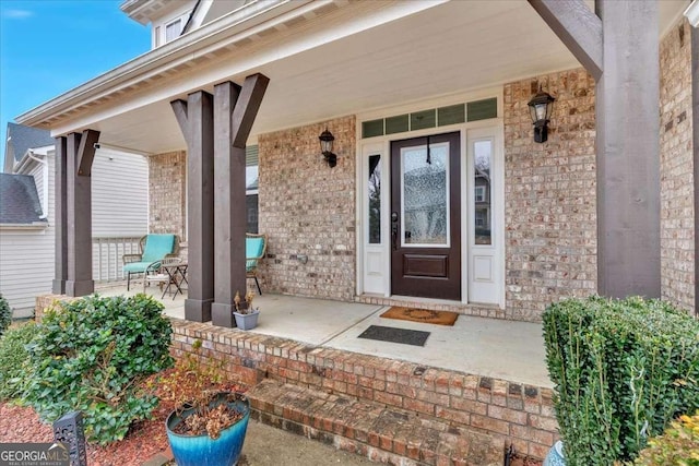 entrance to property featuring brick siding and a porch