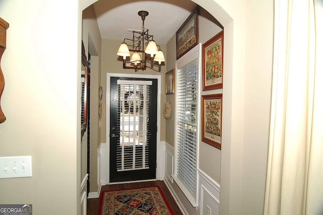 doorway to outside featuring dark wood finished floors and a notable chandelier