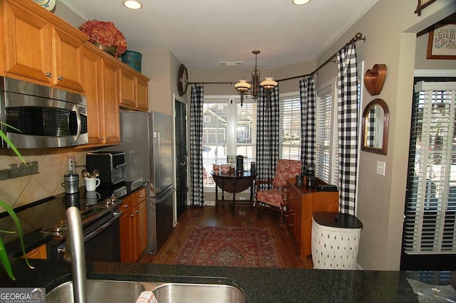 kitchen featuring dark wood-type flooring, backsplash, dark countertops, and appliances with stainless steel finishes