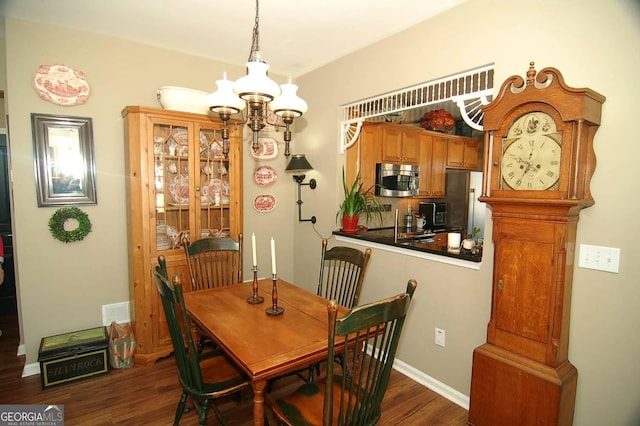 dining space featuring dark wood-style floors, visible vents, baseboards, and an inviting chandelier