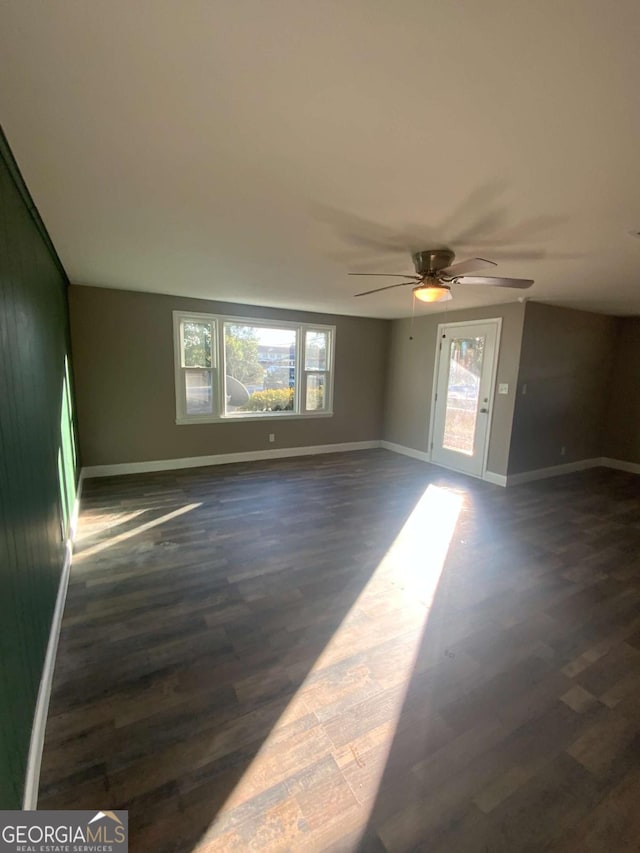 spare room with dark wood finished floors, baseboards, and ceiling fan