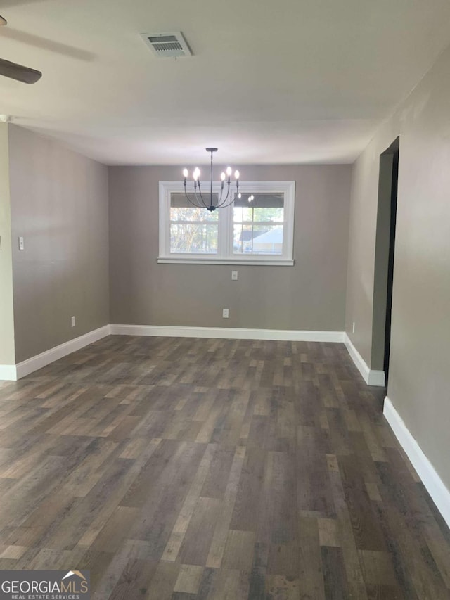 unfurnished dining area featuring visible vents, baseboards, dark wood-type flooring, and ceiling fan with notable chandelier