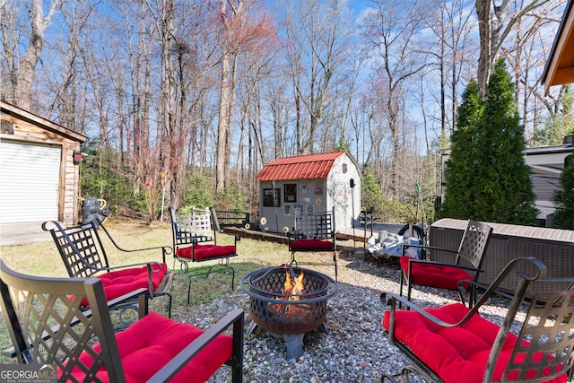 view of patio featuring a fire pit, a storage unit, and an outbuilding