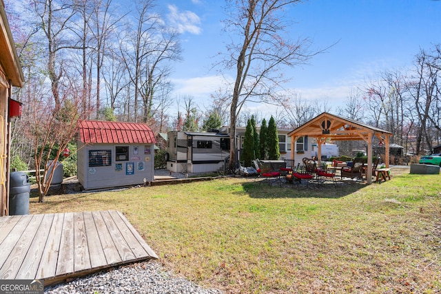 view of yard featuring an outdoor structure, a wooden deck, a gazebo, and a storage unit
