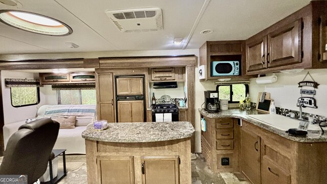 kitchen with black gas stove, light countertops, exhaust hood, and a sink