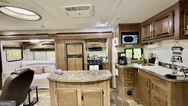 kitchen featuring a sink, light countertops, ventilation hood, and black gas range
