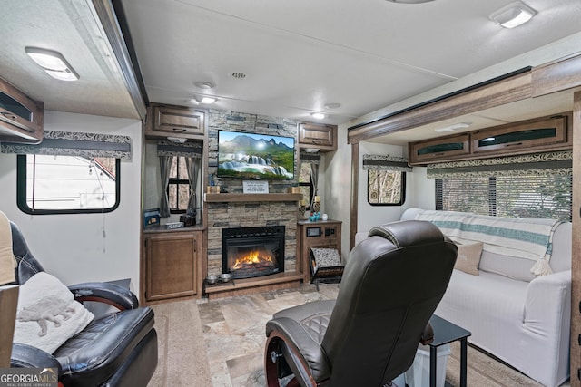 living area featuring a wealth of natural light, stone finish floor, and a fireplace