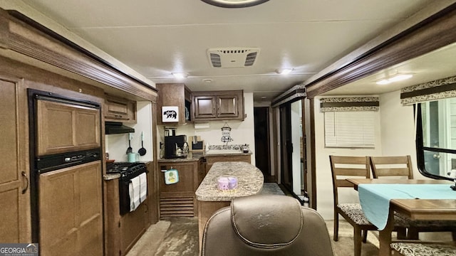 kitchen featuring visible vents, black range with gas stovetop, and light countertops