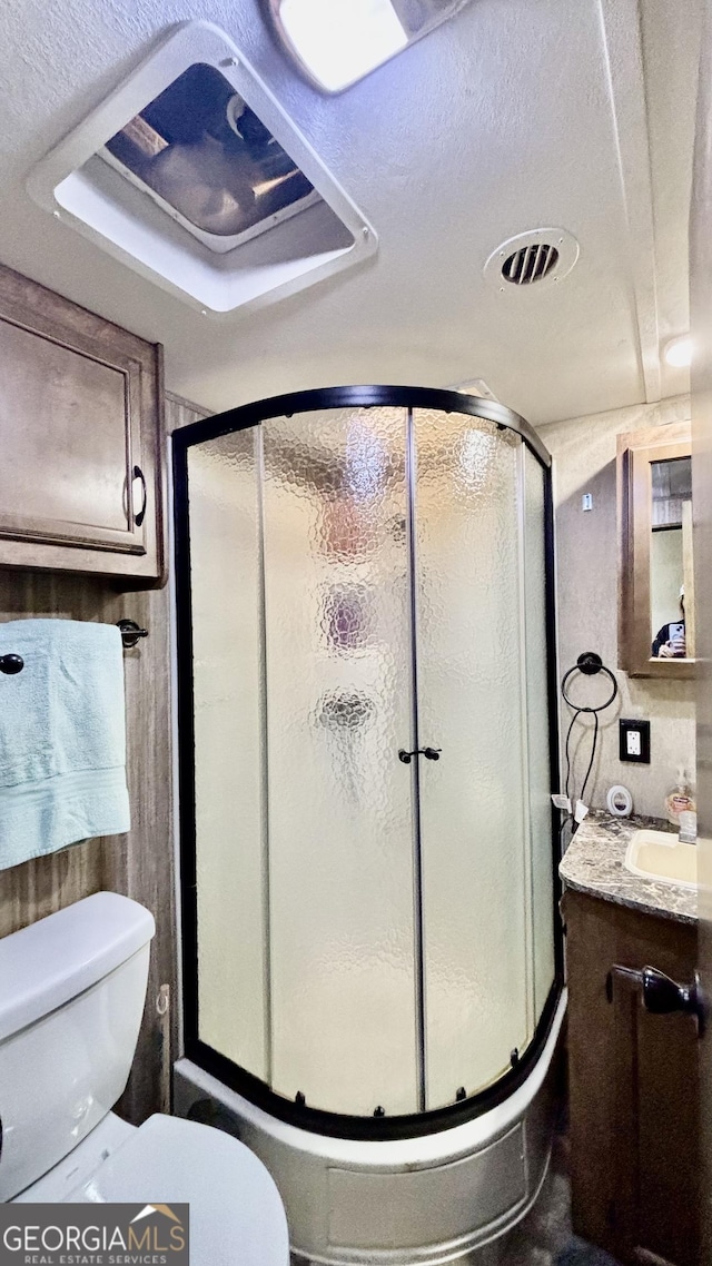 bathroom with visible vents, toilet, a stall shower, and vanity