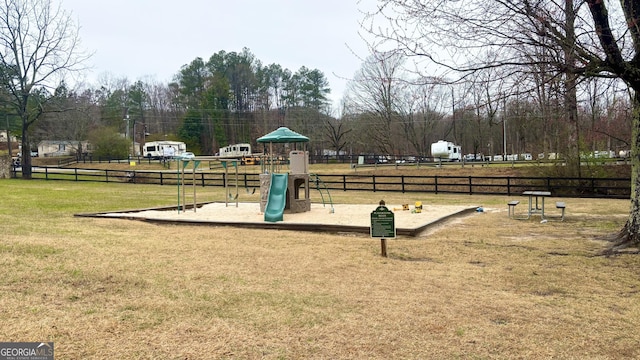 exterior space with fence, playground community, and a lawn