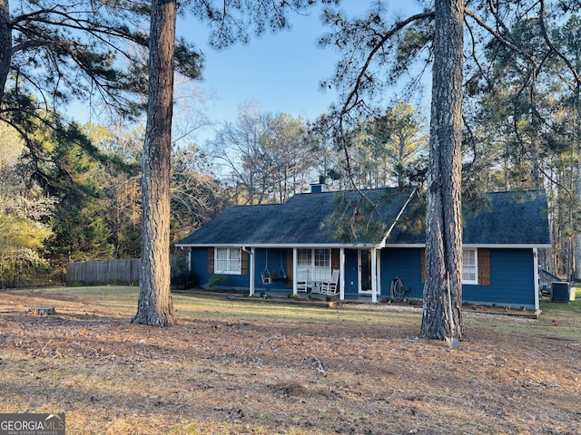 single story home featuring fence, covered porch, a chimney, a front lawn, and central air condition unit