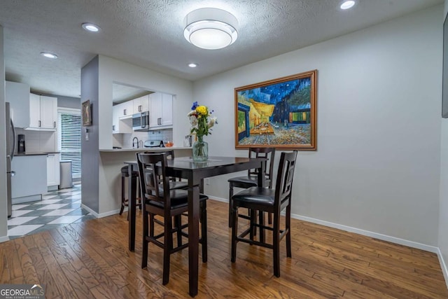 dining room featuring dark wood finished floors, recessed lighting, a textured ceiling, and baseboards