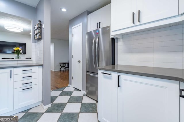 kitchen with dark countertops, dark floors, tasteful backsplash, and freestanding refrigerator