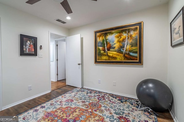 workout room with a ceiling fan, wood finished floors, visible vents, and baseboards