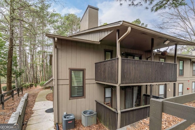 view of property exterior with a balcony, central AC, and a chimney