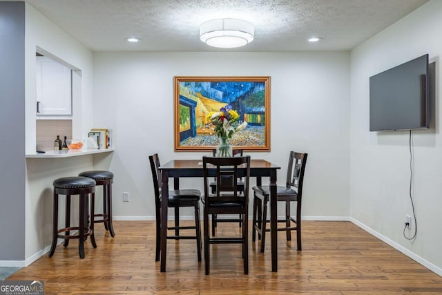 dining space featuring baseboards, a textured ceiling, and wood finished floors