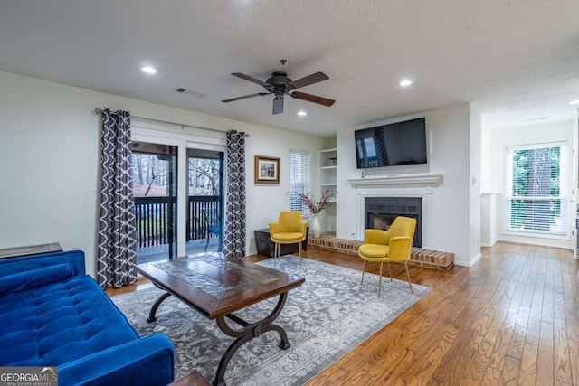 living area with visible vents, recessed lighting, a fireplace, wood-type flooring, and a textured ceiling