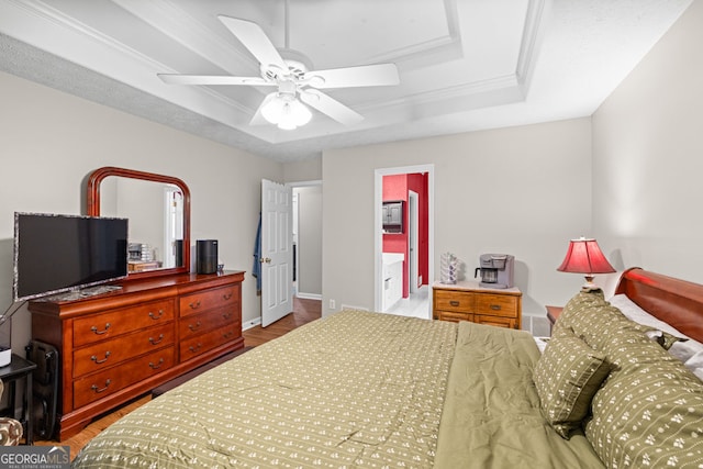 bedroom featuring a tray ceiling, wood finished floors, baseboards, and ornamental molding