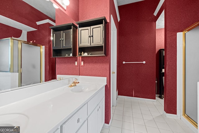 bathroom with baseboards, double vanity, a stall shower, a sink, and tile patterned flooring