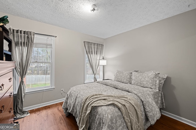 bedroom with baseboards, a textured ceiling, and wood finished floors