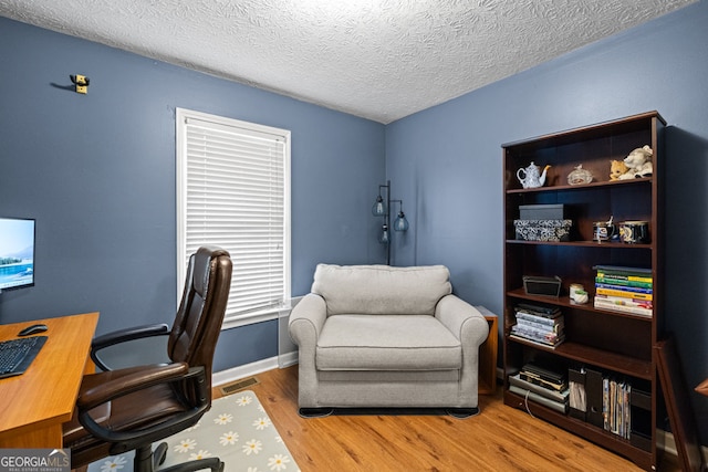 office featuring baseboards, wood finished floors, visible vents, and a textured ceiling