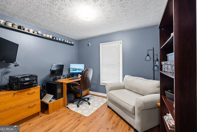 office space with light wood finished floors, a textured ceiling, and baseboards